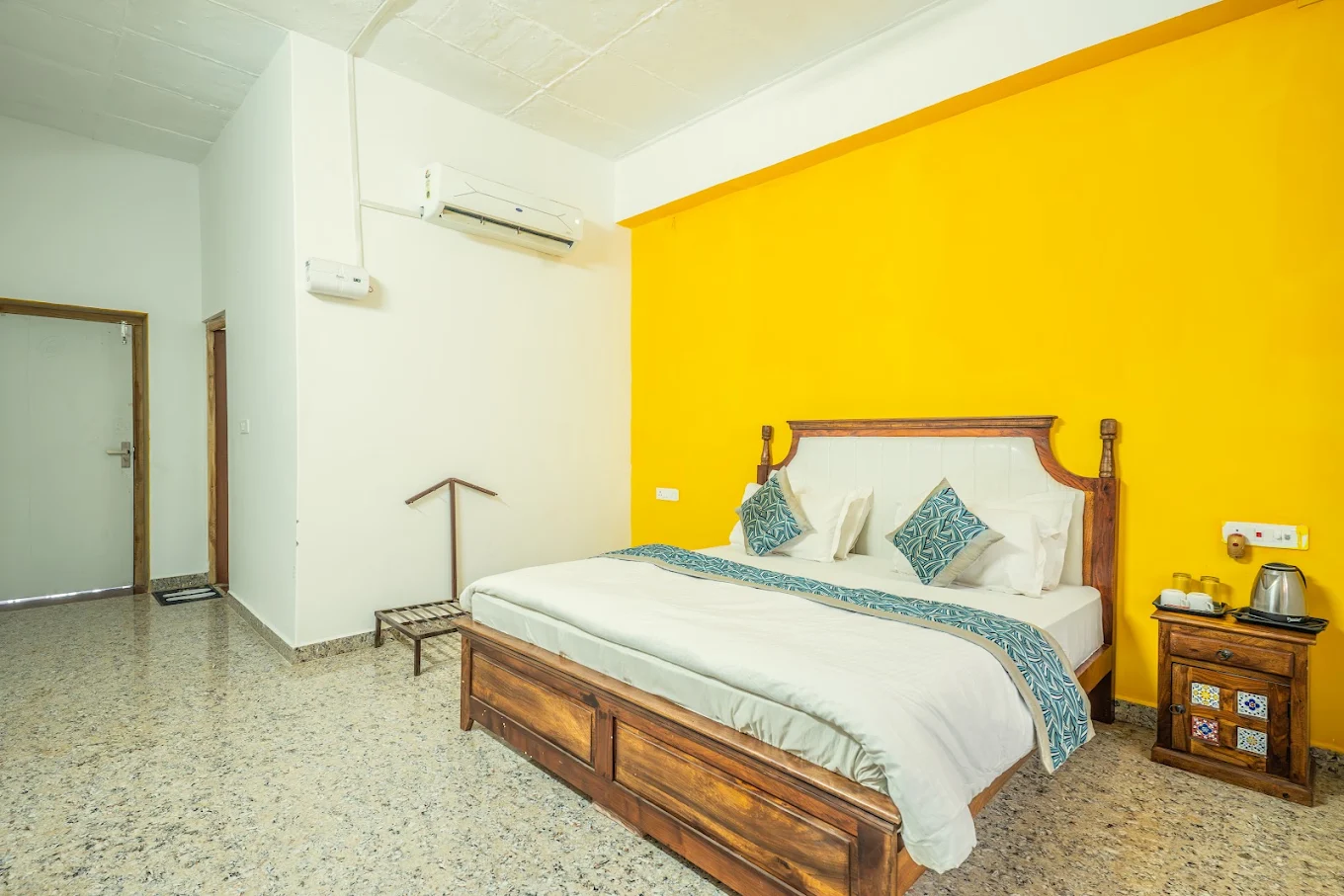 Interior of a Luxury AC Cottage room with a king bed and bright yellow accent wall